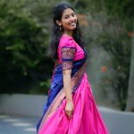 A woman in vibrant traditional Kerala dress smiling in an outdoor setting, showcasing cultural elegance.